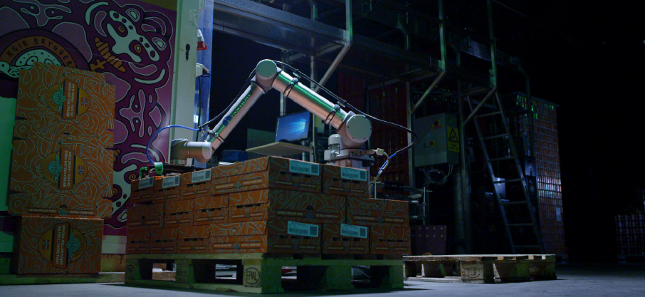 A robotic arm on a pallet of boxes

Description automatically generated